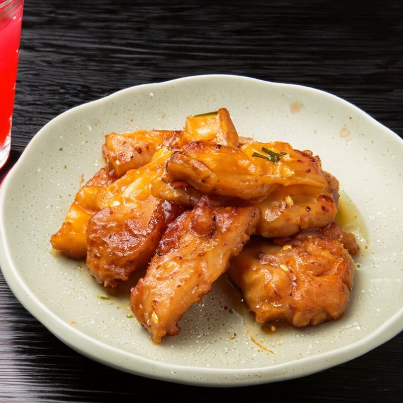 Go HOT Chicken's golden-brown glazed wings on a light plate, with a red drink in the background.