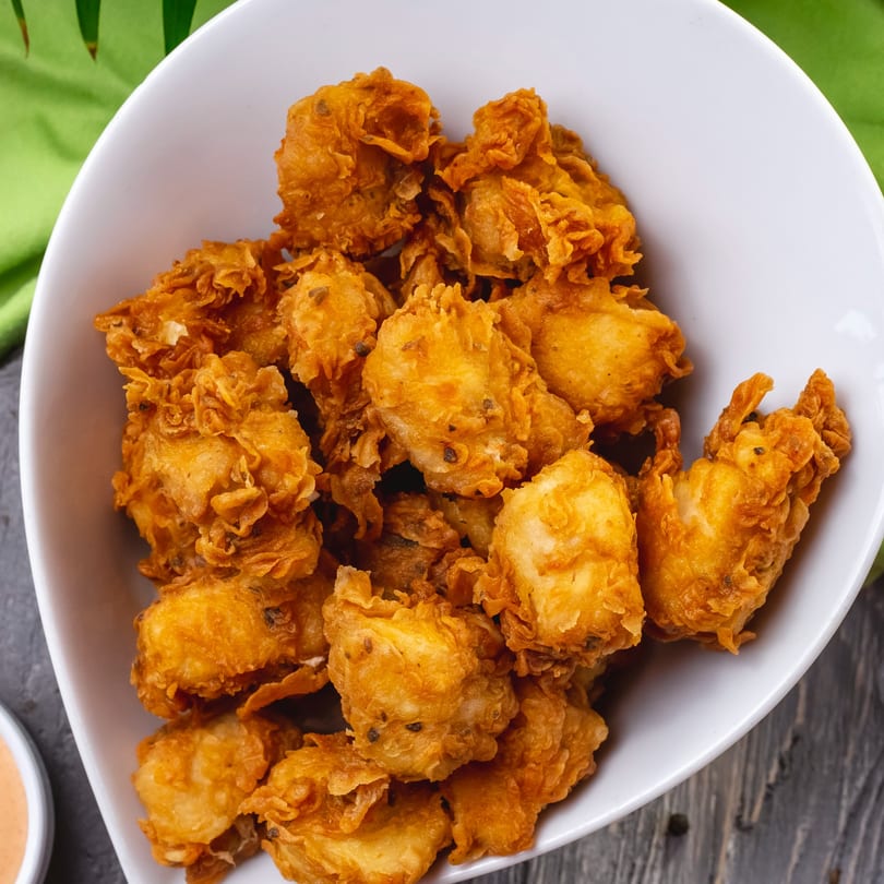A white bowl filled with crispy, golden-brown Go HOT Chicken wings, with a green napkin in the background.